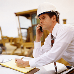 a construction project manager at the phone, taking notes